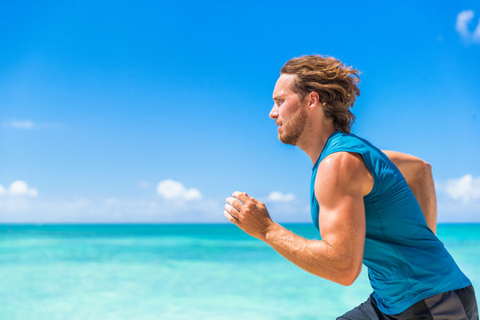 Healthy sport runner man running sprint on beach ocean background. Sports athlete active lifestyle in summer outdoor tropical landscape.