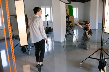 Photographer communicating with male photo model. Studio session backstage.