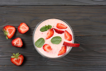 Healthy strawberry yogurt with mint leaves and fresh berries on dark wooden background. Top view with copy space.