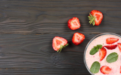 Healthy strawberry yogurt with mint leaves and fresh berries on dark wooden background. Top view with copy space.