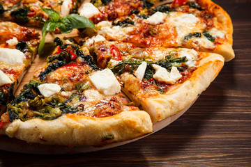 Pizza with feta cheese and spinach on wooden table