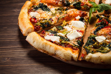 Pizza with feta cheese and spinach on wooden table