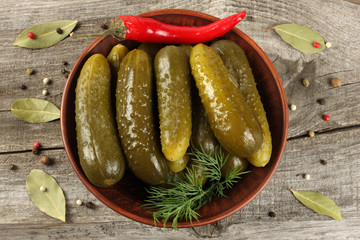 marinated pickled cucumbers in plate with spices on wooden background. top view with copy space
