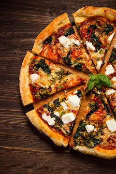 Pizza with feta cheese and spinach on wooden table