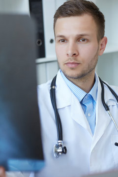 Closeup portrait of a young male doctor looking at x-ray.