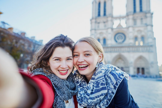 Two young girls taking selfie near Notre-Dame in Paris