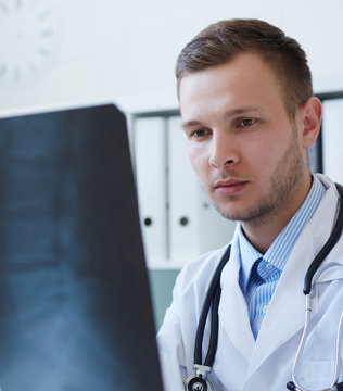 Male doctor studying x-ray image.