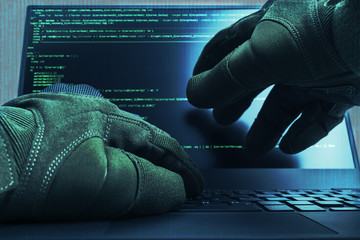 Hacker hands wearing gloves working on a console commands. Internet cyber concept. Green toning.