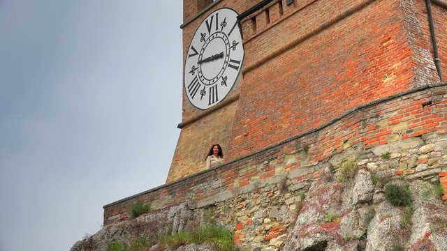 female tourist passing  under clock tower in Brisighella, Italy