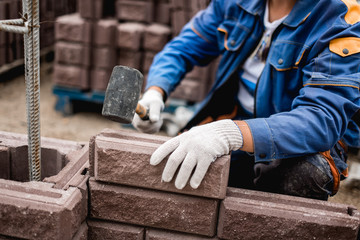 Bricklayer putting down another row of bricks in site