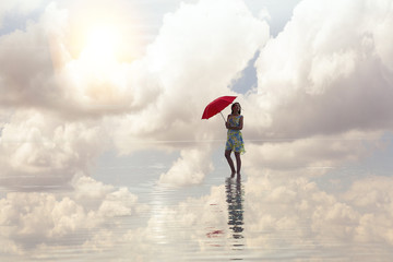 Woman holding red umbrella and walking on the salt lake. Sunrise sea and woman with umbrella in hand