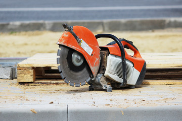 A circular saw for sawing a curb plate lies near a wooden pallet when building a parking lot for tourist buses.