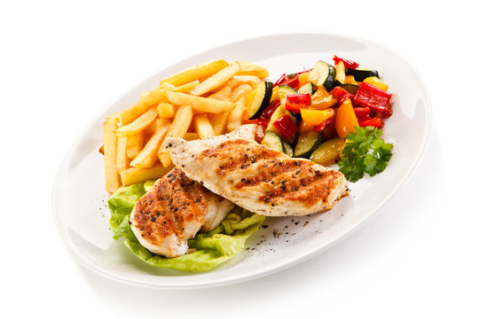 Grilled chicken fillet with french fries on white background