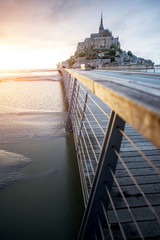 Sunset view on the famous Mont Saint Michel abbey with bridge during the tide in France
