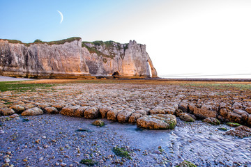 Twilight landscape view on the rocky coastline near Etretat town during the water ebb in France