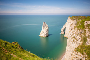 Landscape view on the famous rocky coastline near Etretat town in France during the sunny day. Long exposure image technic with soft water