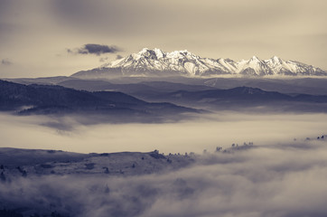 Fototapeta na wymiar B&W morning panorama of snowyTatra Mountains, Poland over misty Spisz highland