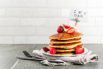 Celebrating Father's Day. Breakfast. The idea for hearty and delicious holiday breakfast: pancakes with butter, maple syrup and fresh strawberries, with congratulations. Coffee cup. Copy space