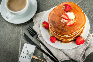 Celebrating Father's Day. Breakfast. The idea for hearty and delicious holiday breakfast: pancakes with butter, maple syrup and fresh strawberries, with congratulations. Coffee cup. Copy space