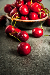 Fresh raw organic seasonal fruits. Cherry with drops of water on a dark stone table. Copy space