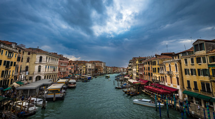 Panoramic view on famous Grand Canal among historic houses in Venice, Italy at dark, cloudy day with dramatic sky. Picture took from the Rialto bridge.