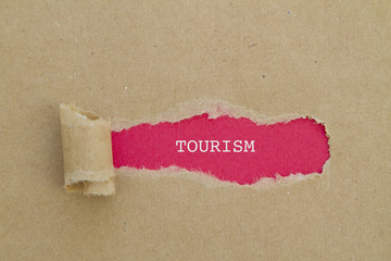 Tourism word written under torn paper.