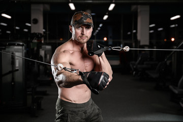 Fototapeta na wymiar Muscular handsome athletic bodybuilder fitness model posing after exercises in gym on diet .
