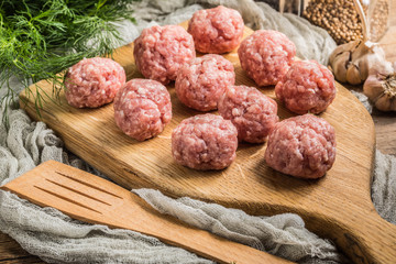 Raw meatballs on the wooden cutting board.