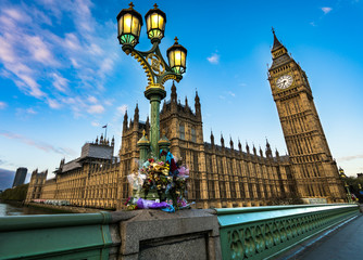 Fototapeta na wymiar Flower tributes for the victims of the March 22,2017 terrorist attack at westminster bridge, big ben and british parliament.