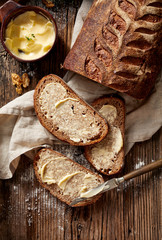 Slices of rustic sourdough bread with homemade butter on wooden table, top view