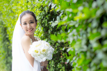 Fototapeta premium beautiful young woman on wedding day in white dress in the tree wall. Female portrait in the park - Selective focus