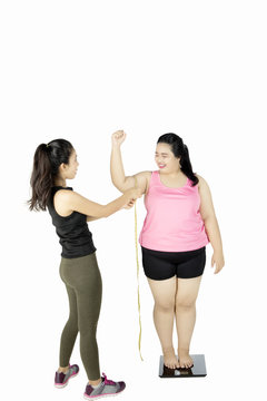 Trainer measuring bicep of fat woman