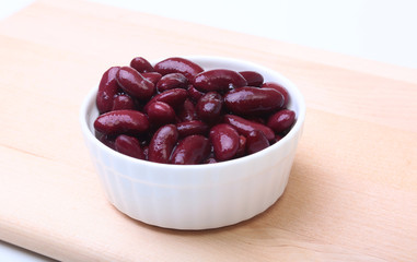 Heap of canned red kidney beans in the sauce in white bowl. vegetarian food. Phaseolus vulgaris.