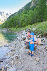 Dad and son are fishing together in a lake in the mountains