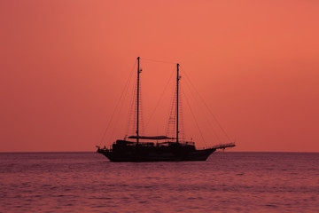 Obraz premium Beautiful red sunset with a sailboat sailing