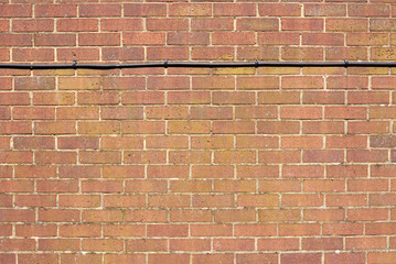 Background of red brick wall pattern with a black cable