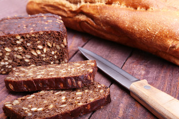 Assorted fresh breads, slice and knife isolated on old wood table.