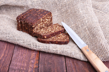 Assorted fresh breads, slice and knife isolated on old wood table.