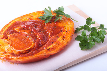 Raw Pork ham with spices and parsley leaves ready for BBQ grilling isolated on white background.