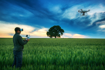 Man with drone wearing VR virtual reality goggles in a field