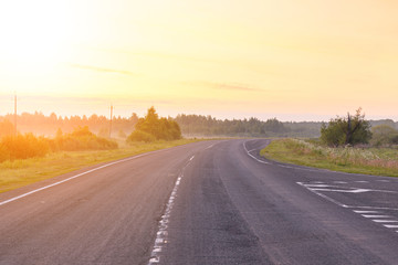 New road in the mist during sunrise in summer