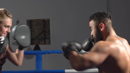 Girl boxer is coached by a man. Boxing sparring in the ring. Slow motion