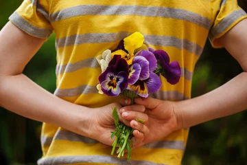 Wall murals Pansies Child hands holding a bouquet pansies flower . Back view.Focus for flowers