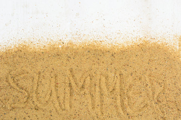 Word 'summer' writing on sand over white wooden background