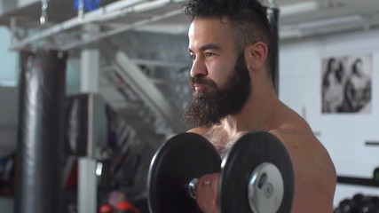 Muscular topless young man doing weightlifting exercises in cross fit gym. slow motion