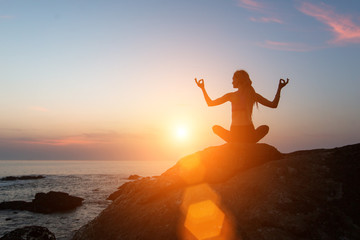 Yoga meditation silhouette. Fitness woman on the ocean during amazing sunset. Healthy lifestyle.