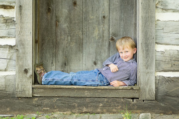 5 year old boy laying in the doorway of an old house 