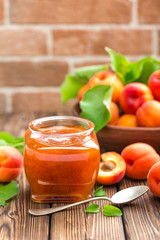 Apricot jam in a jar and fresh fruits with leaves