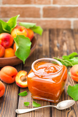 Apricot jam in a jar and fresh fruits with leaves
