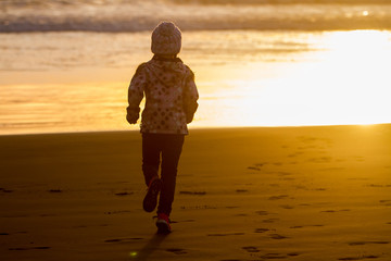 outdoor portrait of young happy smiling child girl in knitted hat on outdoor natural background